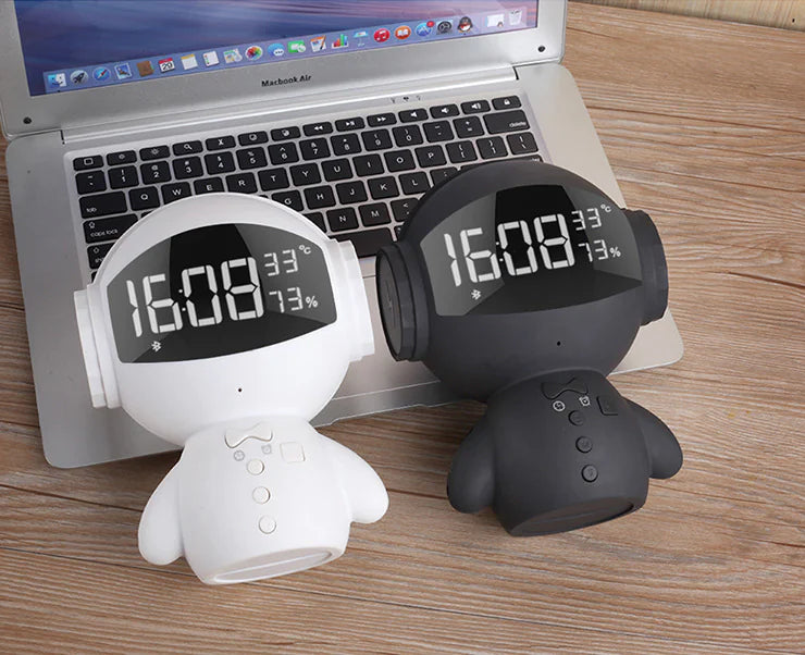 Two digital temperature and humidity monitors, one white and one black, in front of a laptop on a wooden surface.