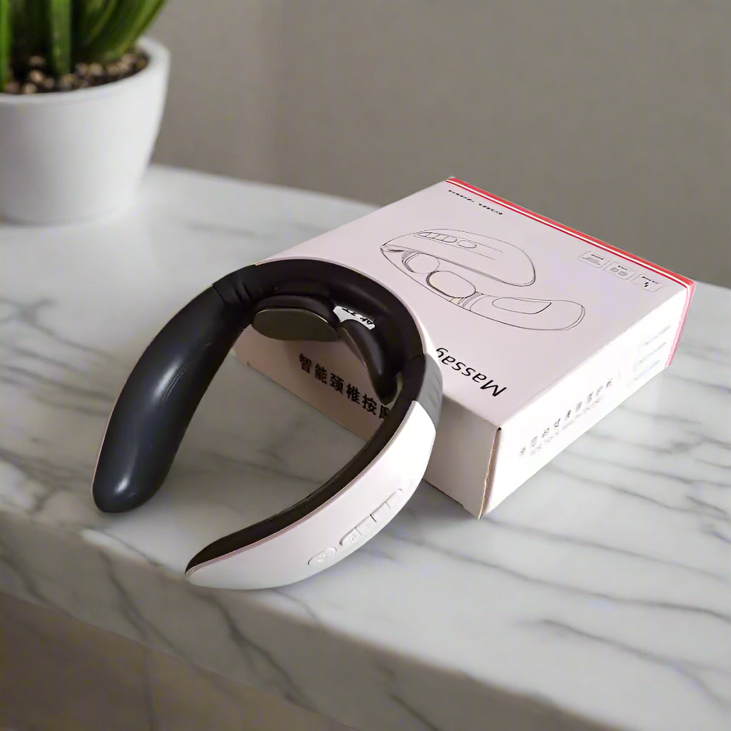 White and black neck massager with packaging on a light gray surface