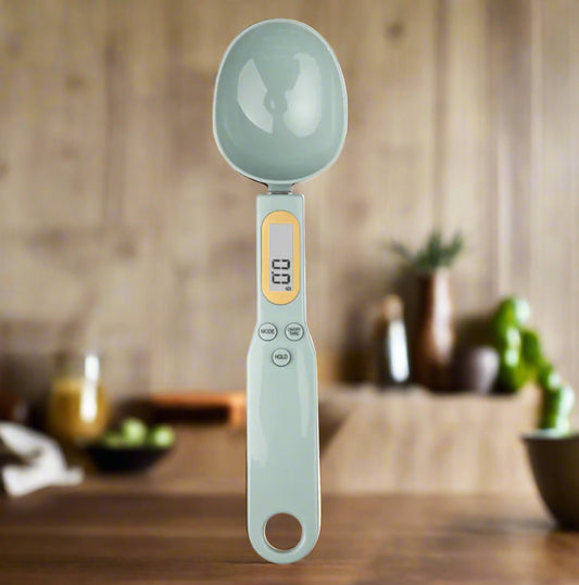 Digital measuring spoon with a light green handle and head on a white background
