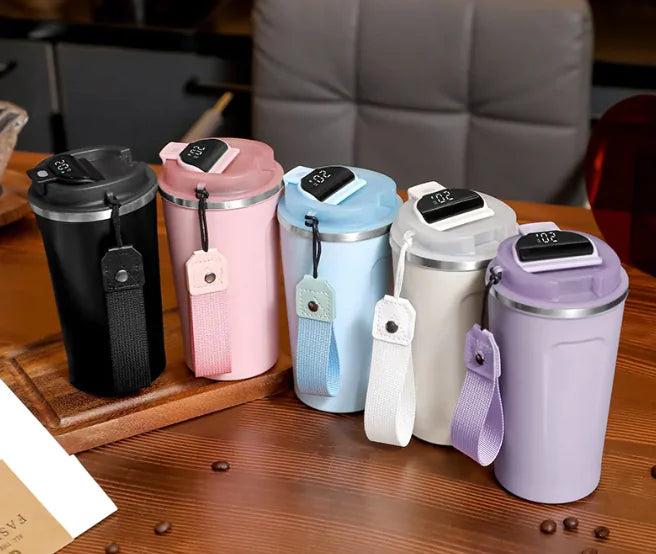 Set of colorful insulated travel mugs on a wooden surface with a blurred background.
