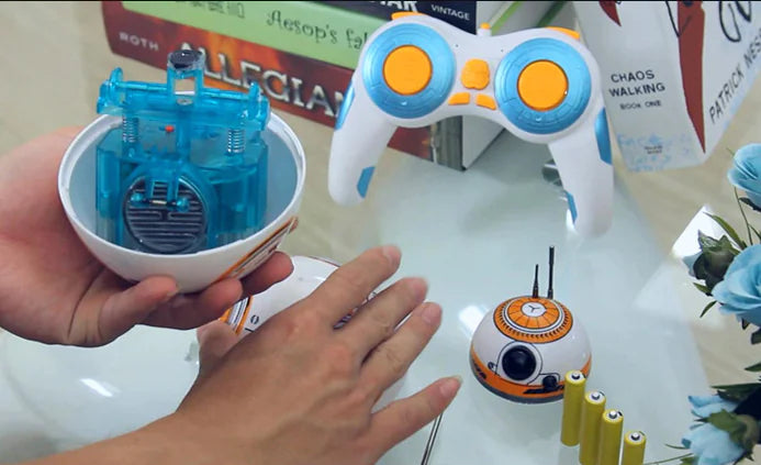 Toy robot, control device, and small robot on a table with a hand interacting.