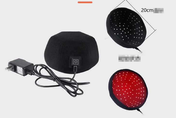 Black head massager with red light, power adapter, and cable on a white background