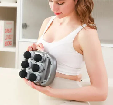 Woman using a handheld massager on her arm in a home setting