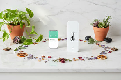 Smart device for temperature and humidity monitoring with smartphone app on a white background