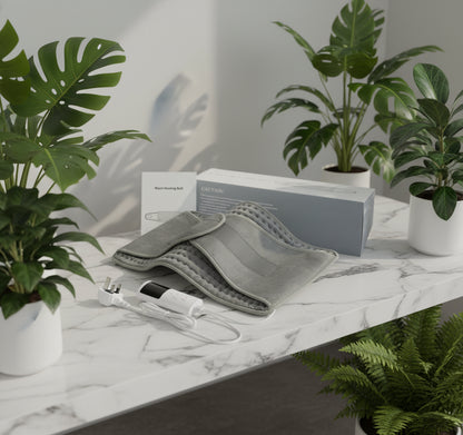 Gray heating pad with power cord and packaging on a white background